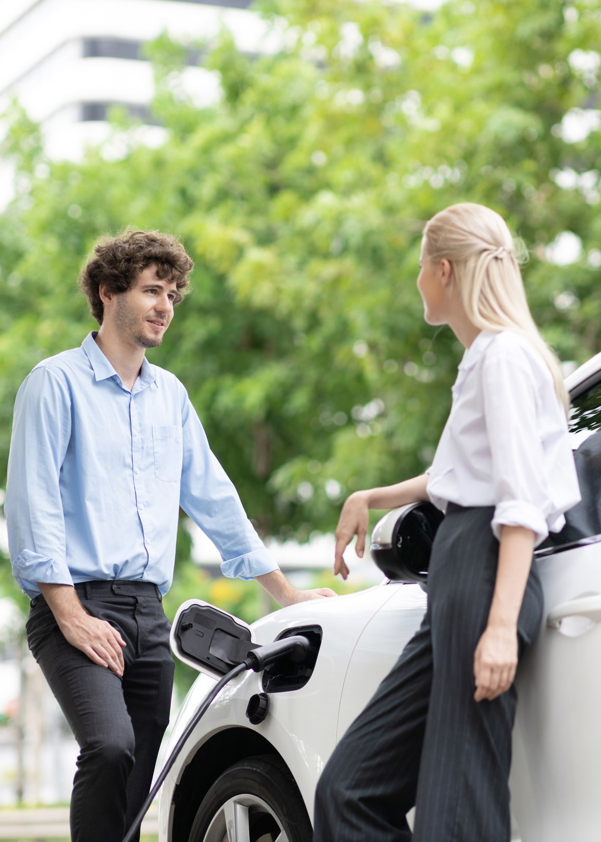 Ein BIld mit einer Frau und einem Mann, die ein Elektroauto laden. Ein BIld mit einer Frau und einem Mann, die ein Elektroauto laden.